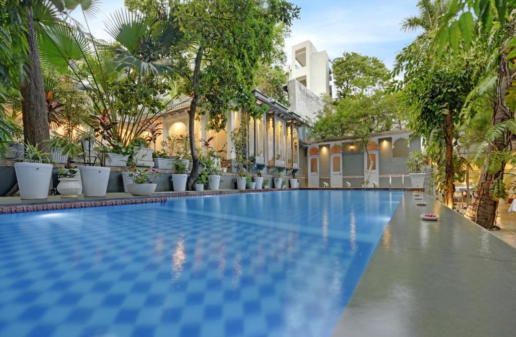una piscina en un complejo con árboles y plantas en Hotel Raj Palace by Howard, en Udaipur