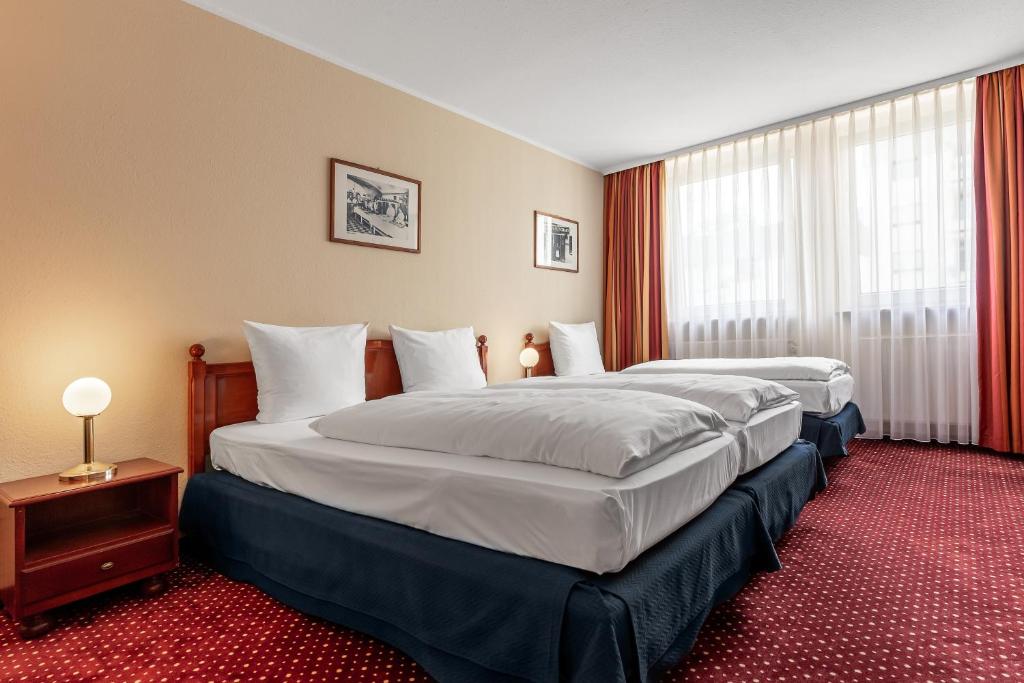 ニュルンベルクにあるアジムット ホテル ニュルンベルクのベッド2台と窓が備わるホテルルームです。