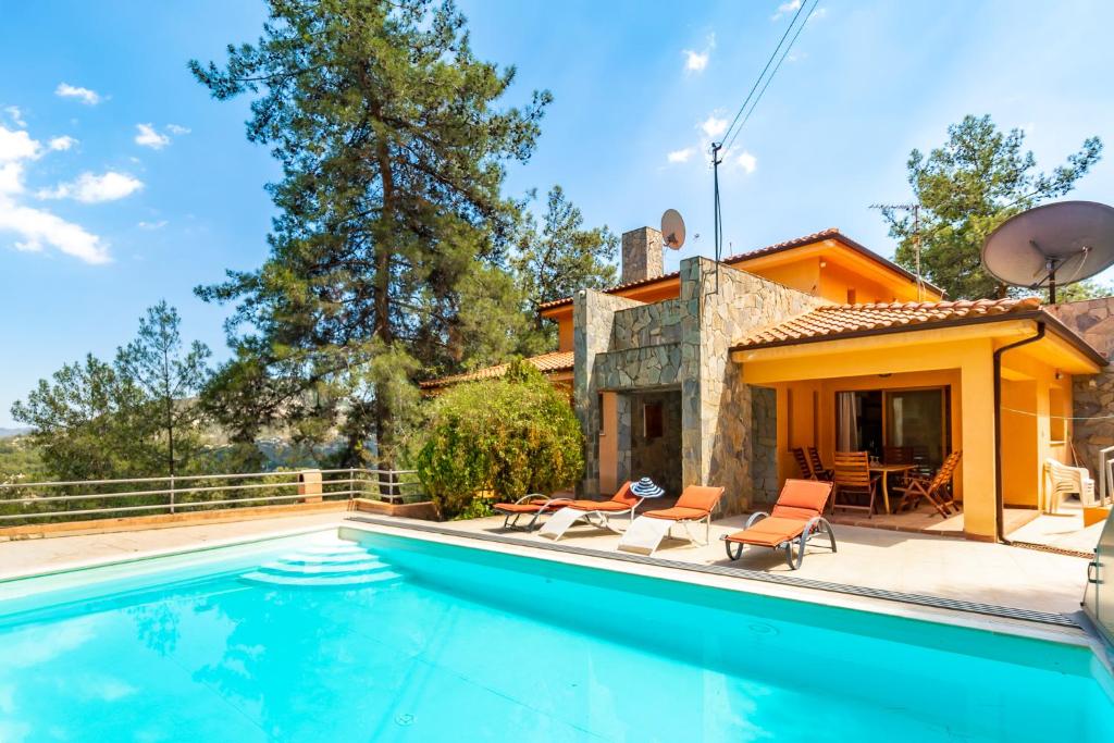 a swimming pool in front of a house at Villa Hillcrest Panorama by Ezoria Villas in Moniatis