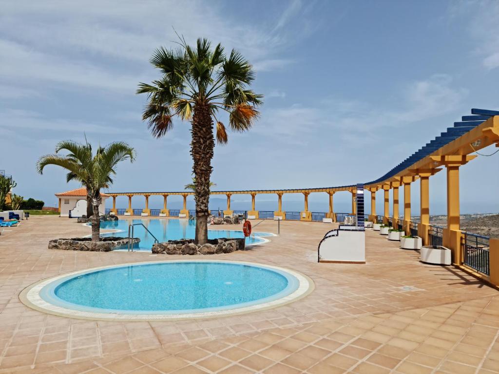 een resort met een zwembad en palmbomen bij Cozy 2 Bedroom Apartment in Costa Adeje in Adeje