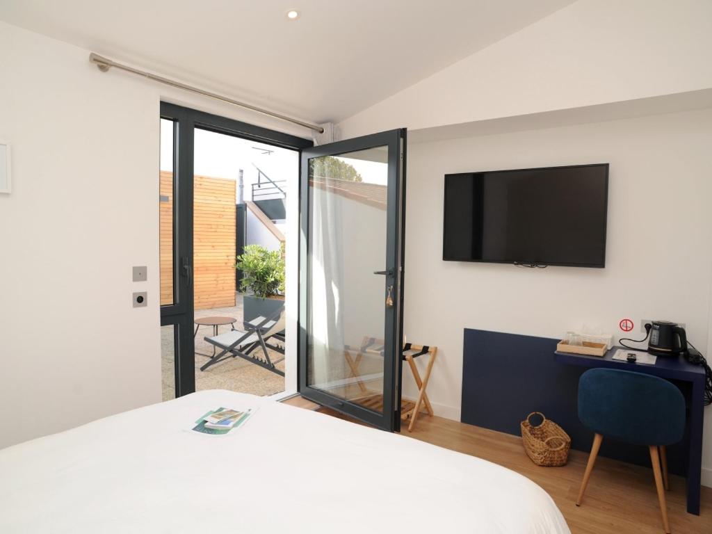 Schlafzimmer mit einem Bett und einem Flachbild-TV in der Unterkunft Hôtel Les Mouettes in La Couarde-sur-Mer