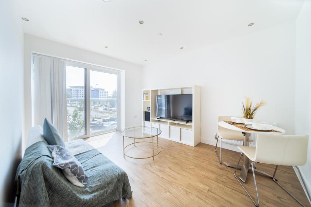 een witte woonkamer met een bank en een tafel bij LiveStay-Modern One Bed Apartment in Private Building in Luton