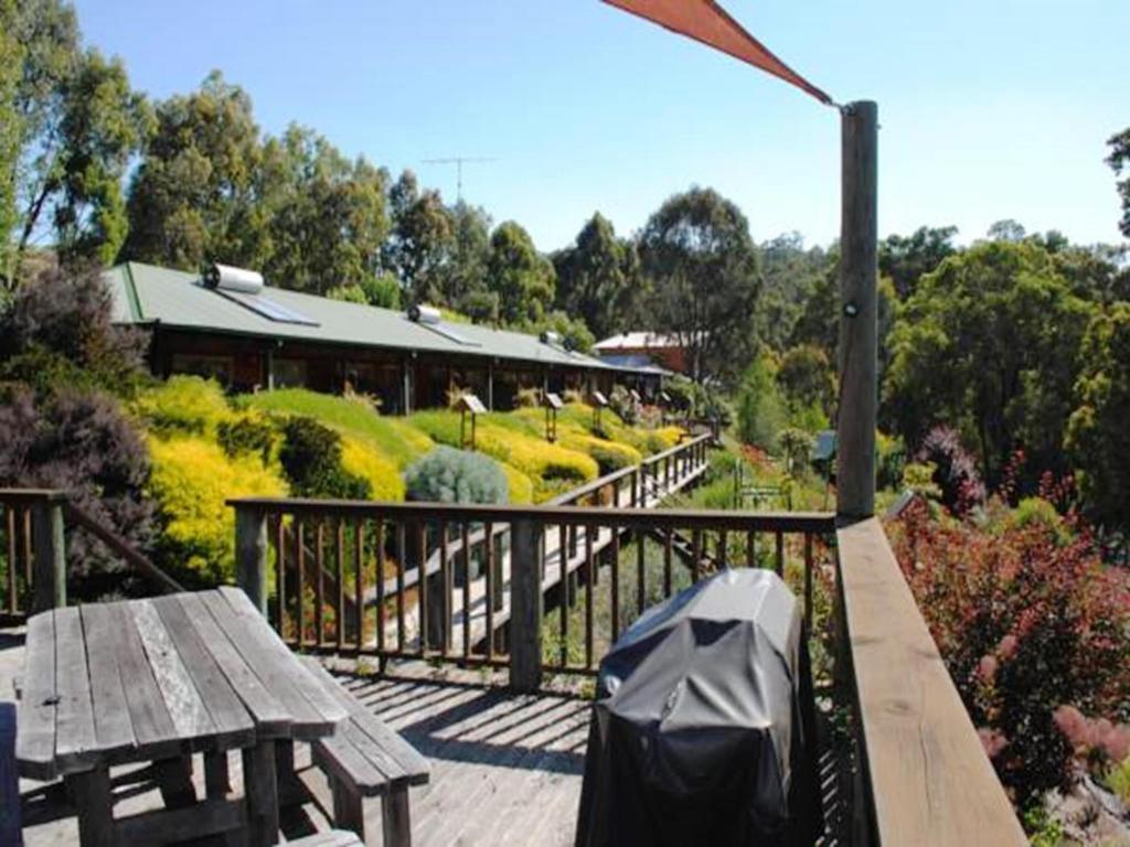 a wooden deck with a wooden table and a bench at Tweed Valley Lodge in Bridgetown