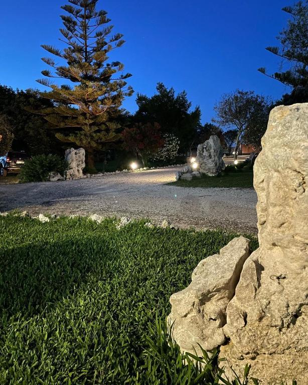 a rock in the grass with a tree in the background at Agriturismo Tenuta Pozzello in Torre dell'Orso