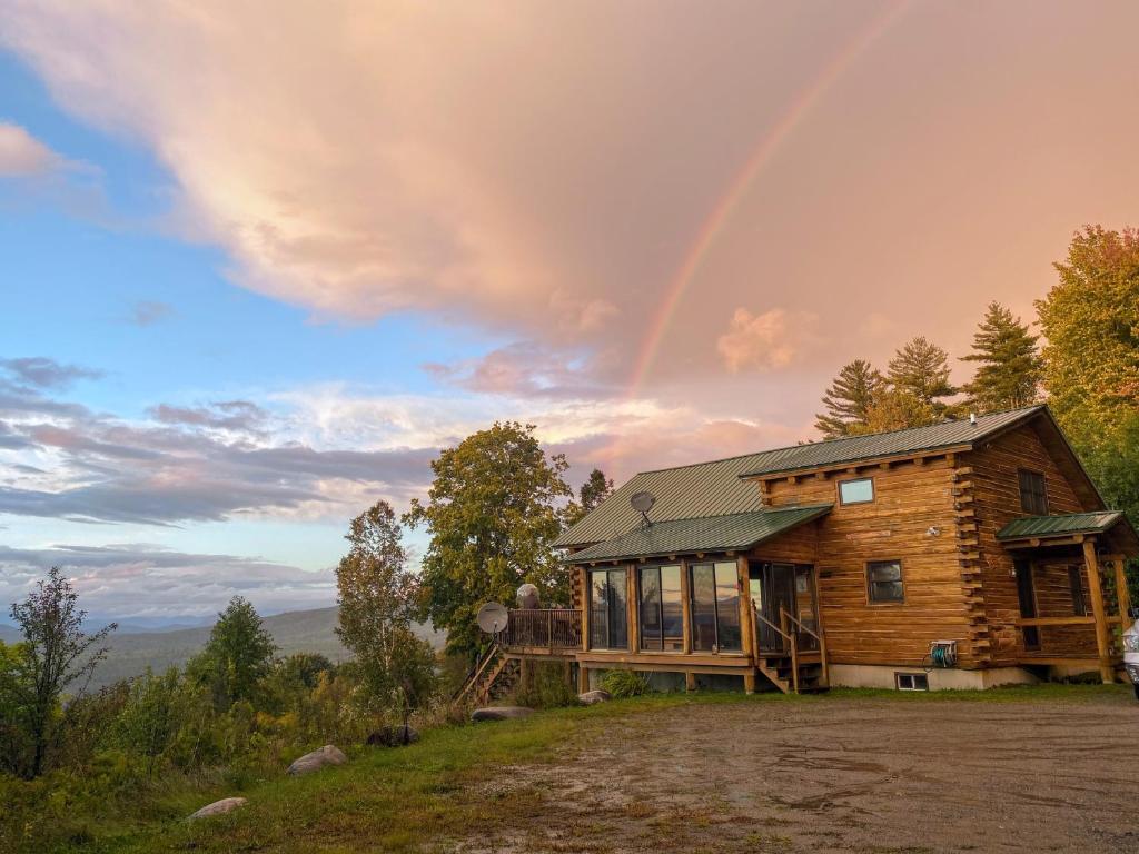 a wooden house with a rainbow in the sky at SI INCREDIBLE VIEWS from this log cabin with large deck huge yard fire pit hot tub in Dalton