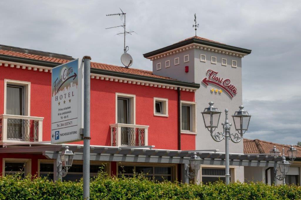 un bâtiment rouge et blanc avec un panneau devant lui dans l'établissement Hotel Fuori Città, à Stanghella