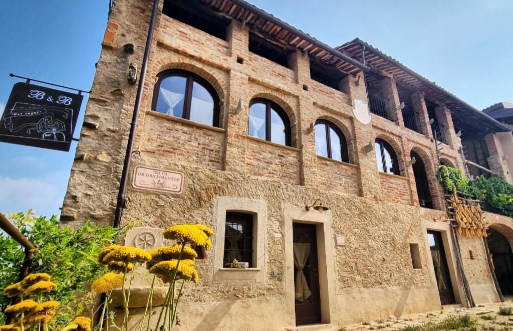 Lesegno的住宿－Per Sognare Per Sugnè，前面有黄色花的砖砌建筑