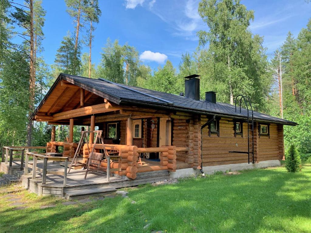 a log cabin in the woods with a grass yard at Lappalaisen lomamökit Lepola in Puumala