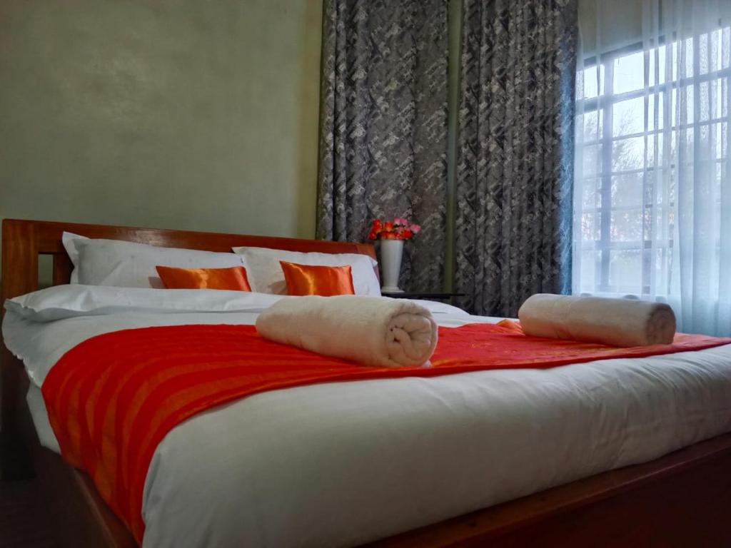 cama grande con sábanas rojas y blancas y ventana en Kioka gardens - stand alone with wifi and parking en Nanyuki