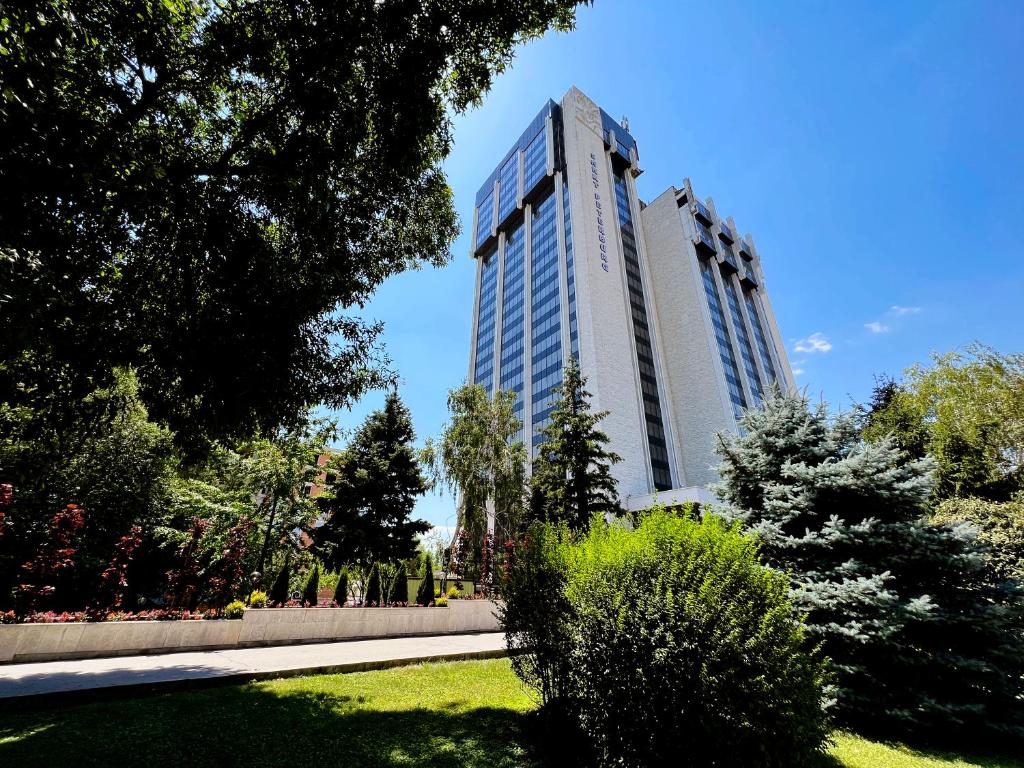 two tall buildings in a park with trees and grass at Park Hotel Sankt Peterburg in Plovdiv