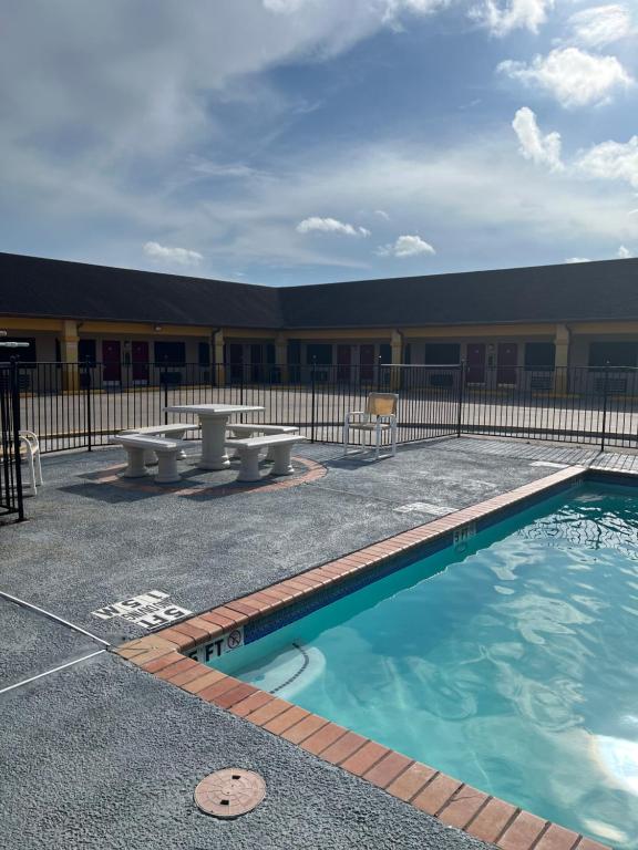 a pool in front of a building with benches at Los Fresnos Inn and Suites in Los Fresnos