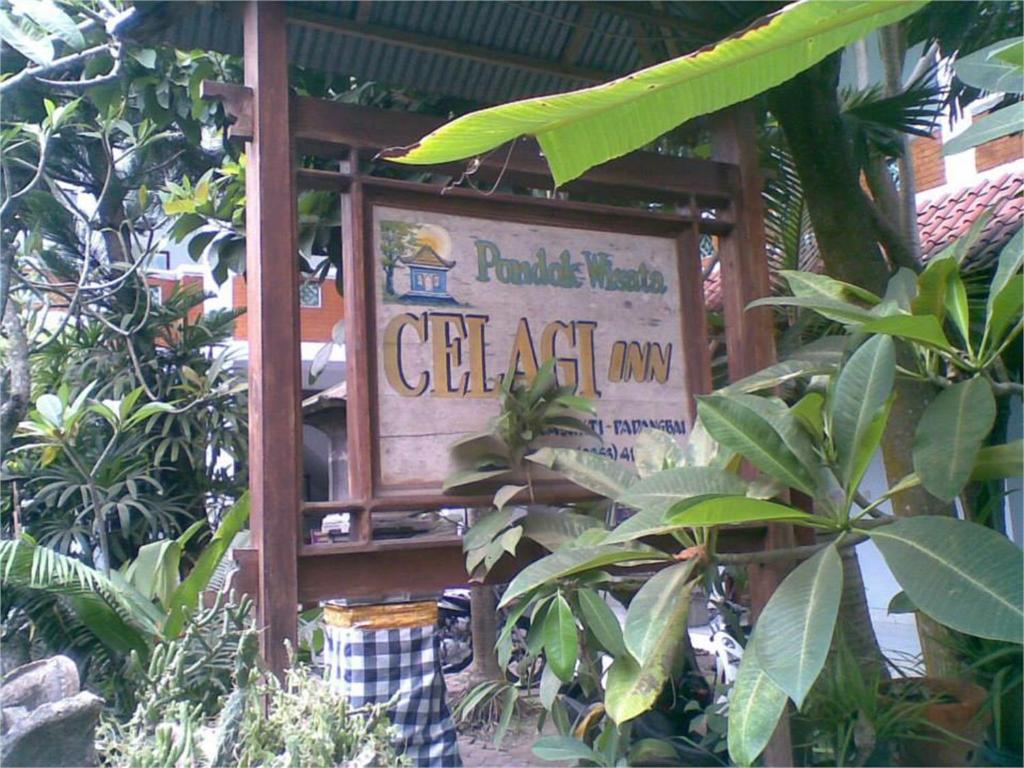 a sign in the middle of a garden with plants at Celagi Inn in Padangbai