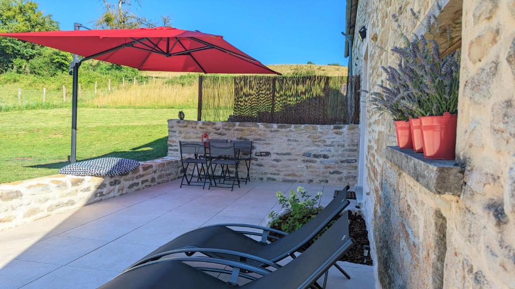 a patio with a red umbrella and chairs and a table at Le petit Moulin de la Motte in Bellenot-sous-Pouilly