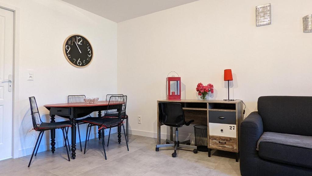 a living room with a table and a clock on the wall at Le petit Moulin de la Motte in Bellenot-sous-Pouilly