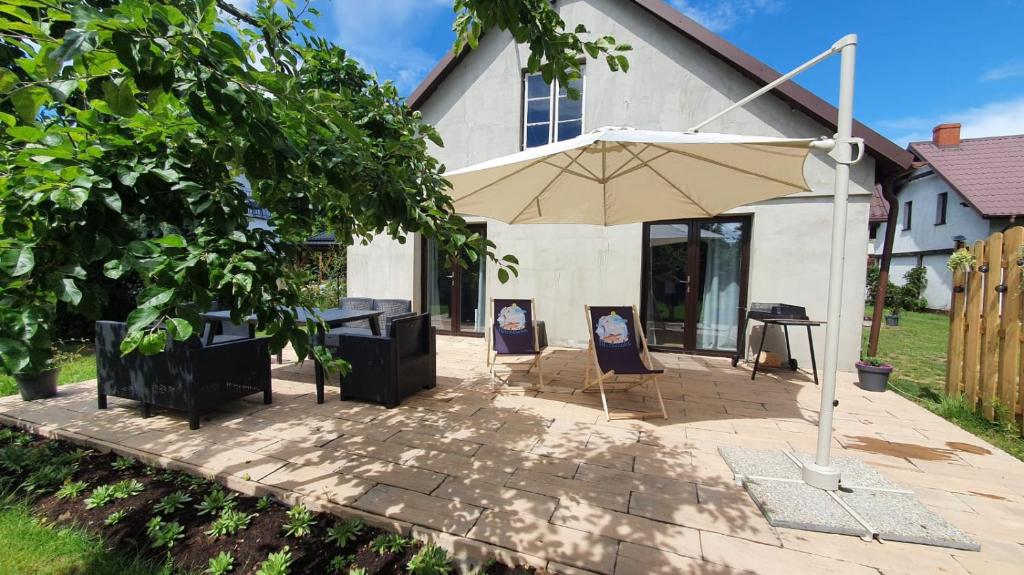 une terrasse avec un parasol en face d'une maison dans l'établissement Michówka, à Mikoszewo