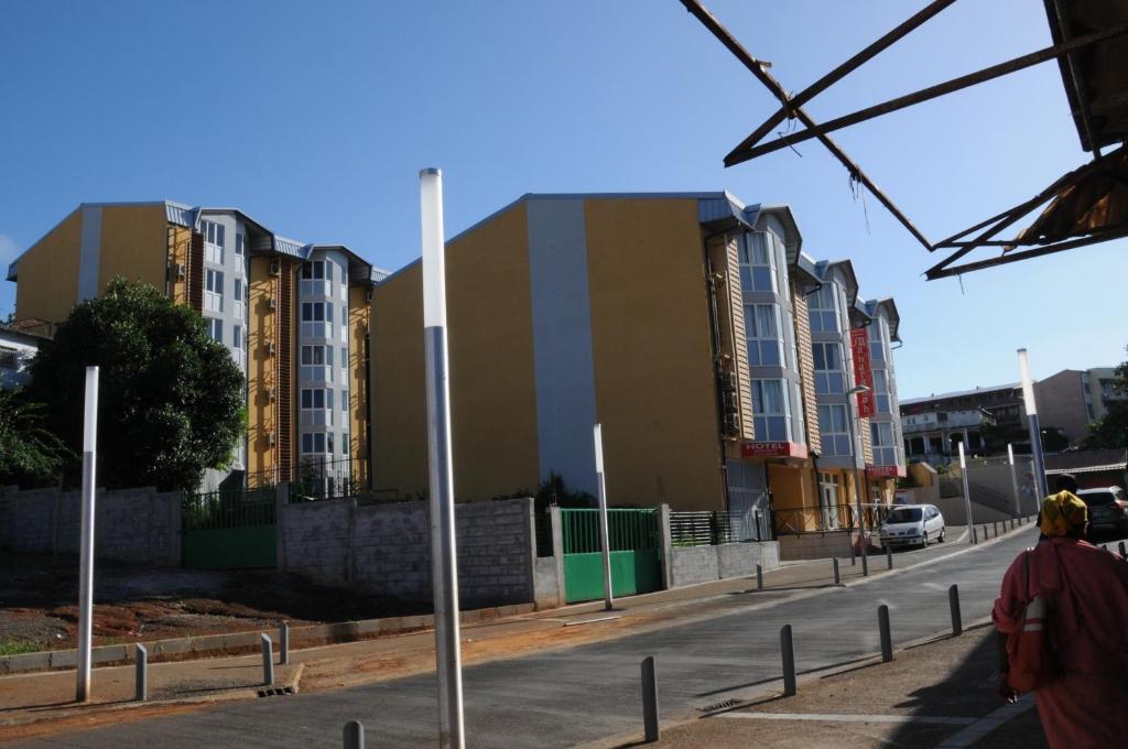 a person walking down a city street with buildings at Hotel Maharajah in Mamoudzou