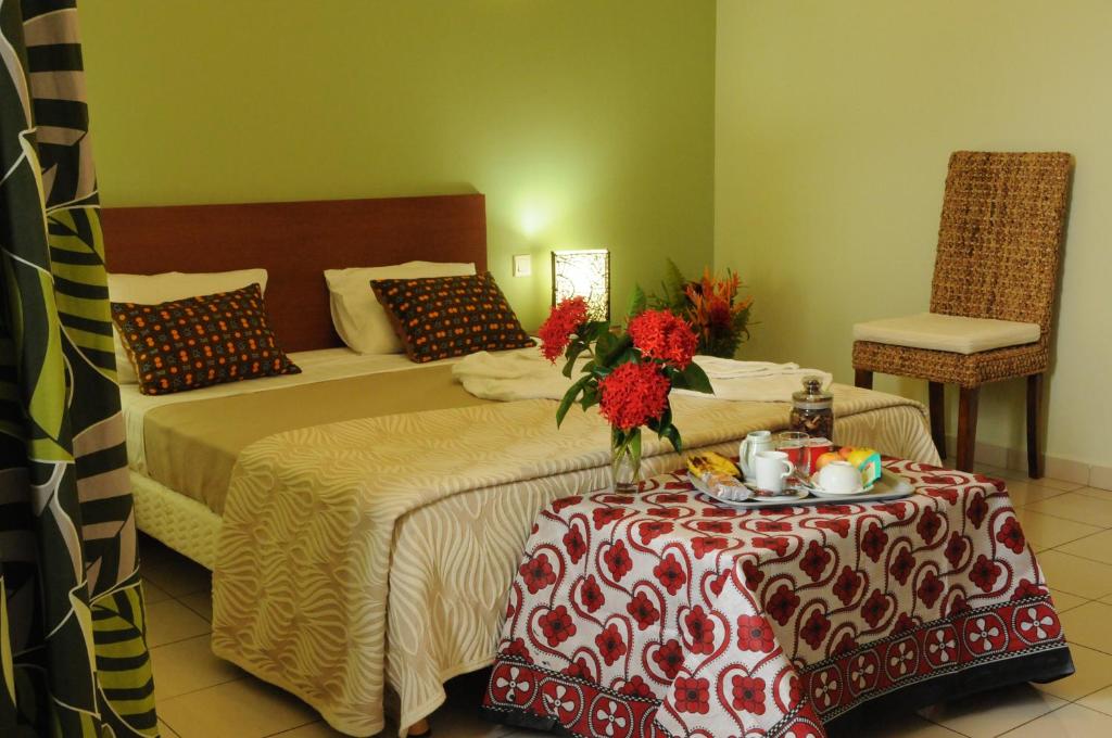 a hotel room with a bed and a table with flowers on it at Hotel Maharajah in Mamoudzou