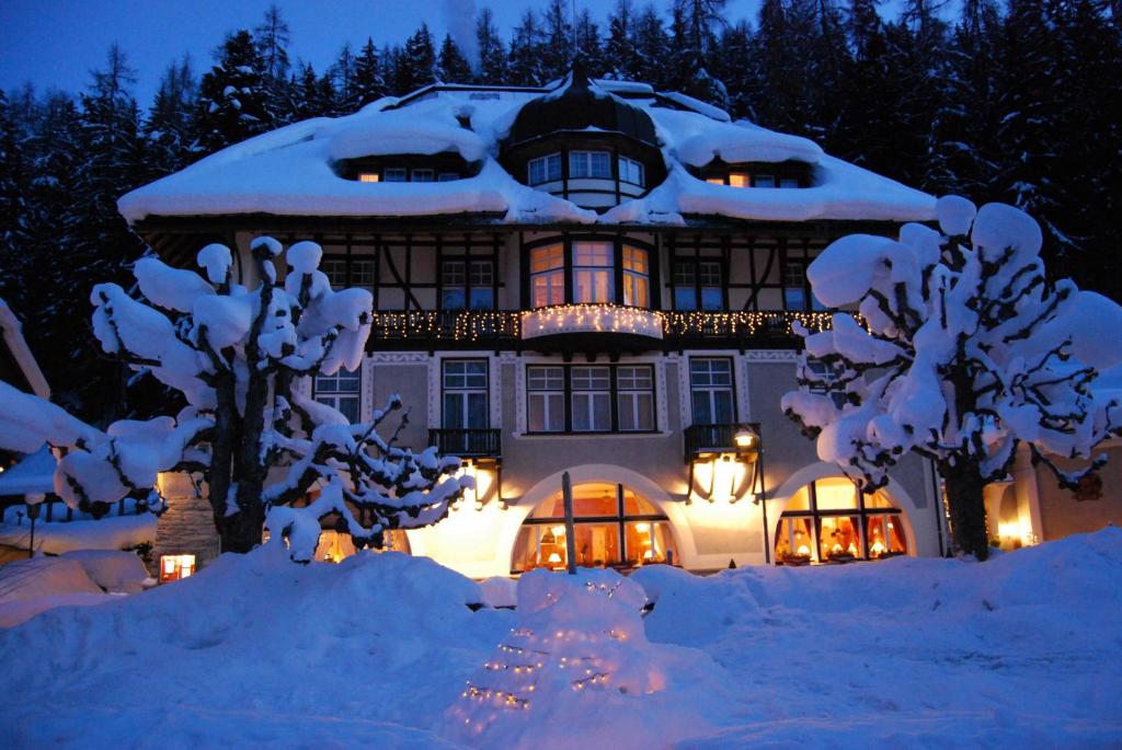 a large house covered in snow at night at Hotel Villa Post in Vulpera