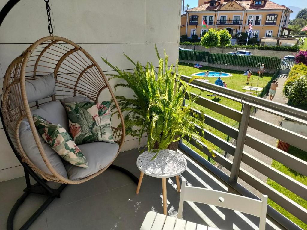 a porch swing with a chair and a table at Apartamentos Boutique Arquera Golf I in Llanes