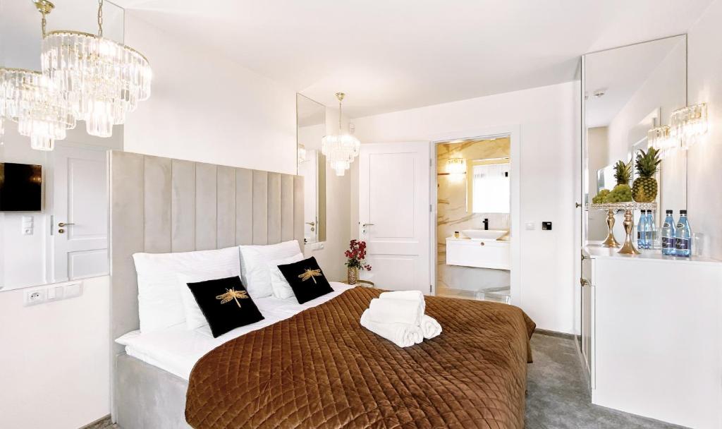 biała sypialnia z dużym łóżkiem i żyrandolem w obiekcie Złota Nuta Villa w mieście Mikołajki