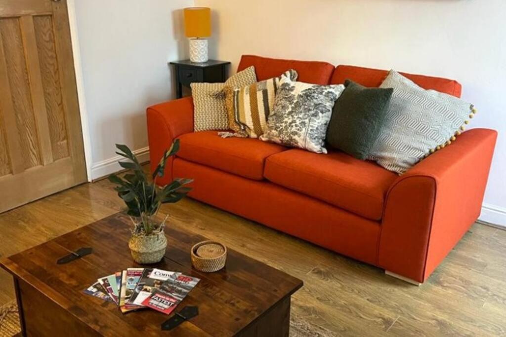 an orange couch in a living room with a coffee table at Cosy 2 bed terraced house in Conwy in Conwy