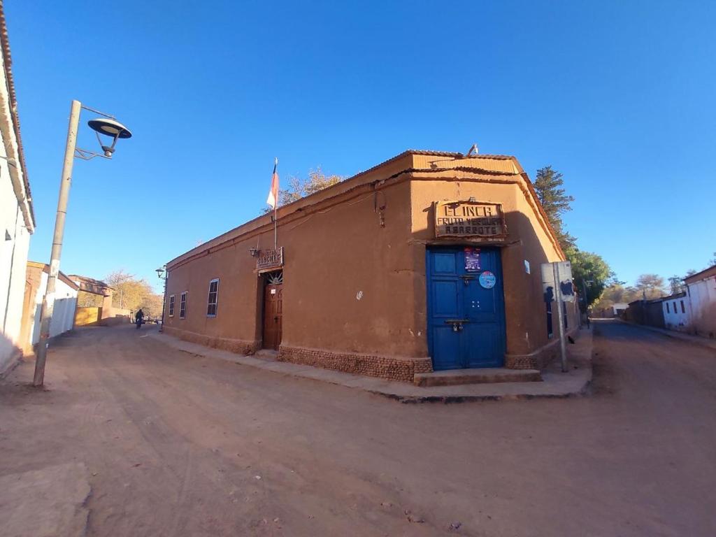 an old building with a blue door on a dirt road at Hostal Sonchek in San Pedro de Atacama