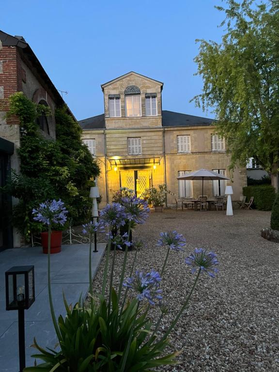 un grand bâtiment avec des fleurs violettes en face dans l'établissement Chambres d'hôtes Les Perce Neige, à Vernou-sur-Brenne