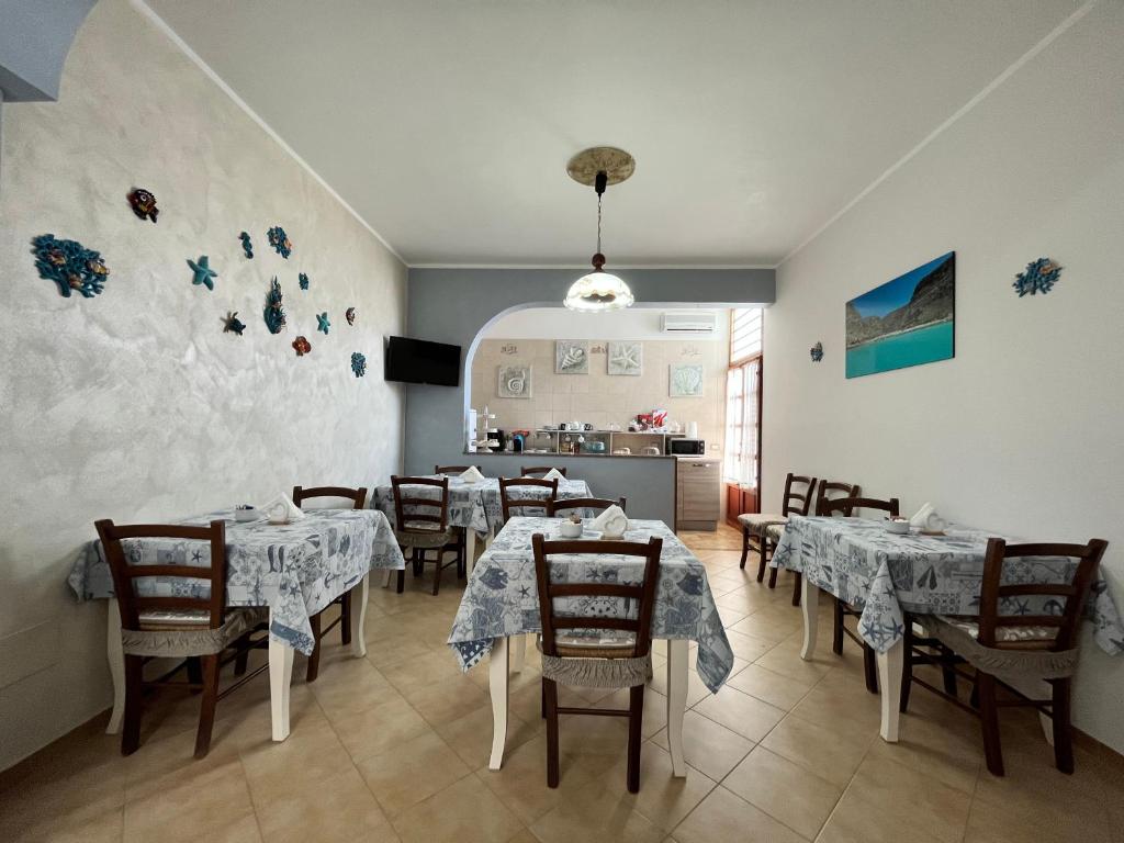 une salle à manger avec des tables et des chaises ainsi qu'une cuisine dans l'établissement Bed and Breakfast Siciliamuri Lampedusa, à Lampedusa