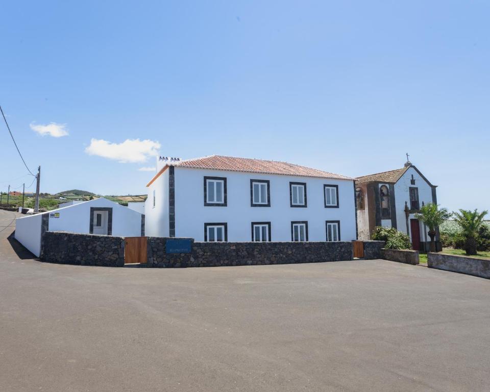 a large white building with a fence in front of it at Casa dos Romeiros in Santa Bárbara