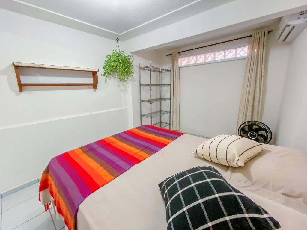 a bedroom with a bed with a colorful blanket at Tiny House in Pipa