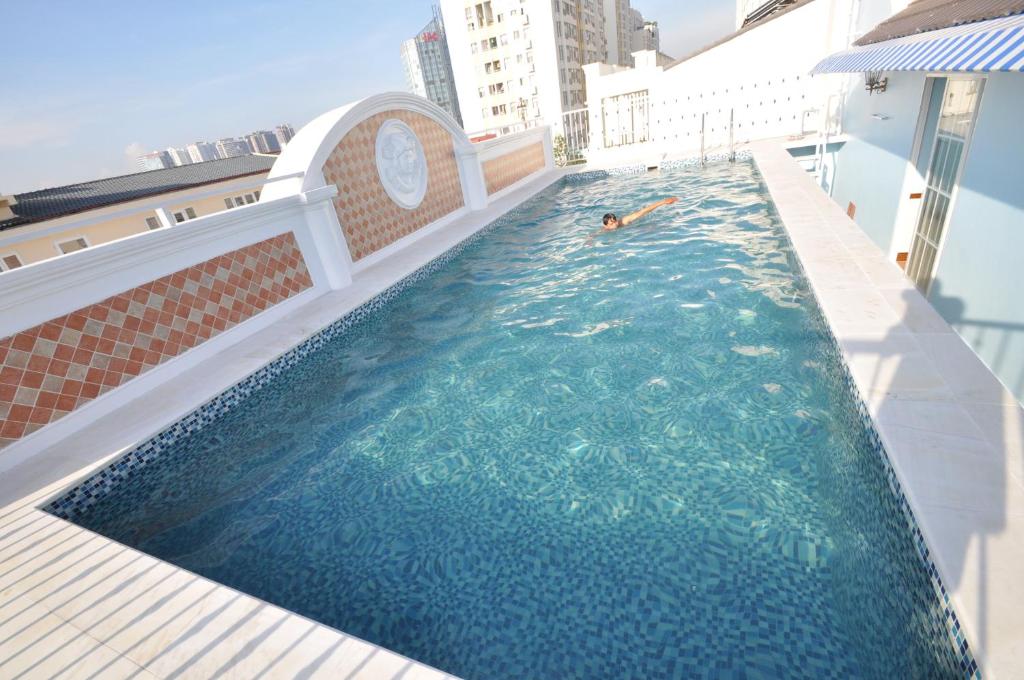 une personne se baignant dans une piscine au-dessus d'un bâtiment dans l'établissement Central Hotel & Residences Swimming Pool, à Hô-Chi-Minh-Ville