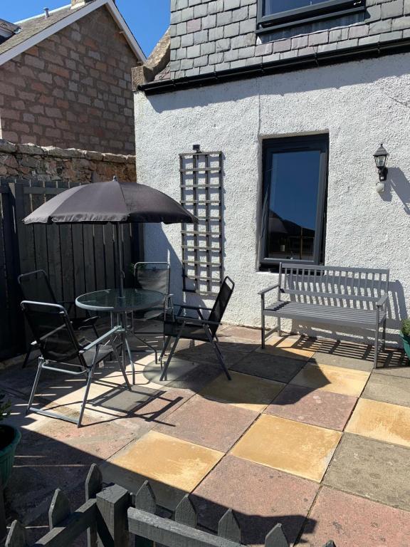 a patio with a table and chairs and an umbrella at Pannanich View Cottage, Ballater in Ballater