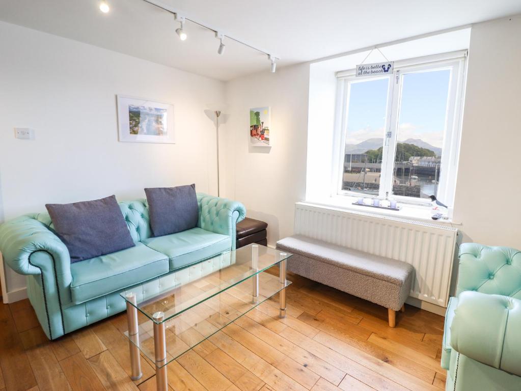 uma sala de estar com dois sofás azuis e uma janela em Harbour Suite em Porthmadog