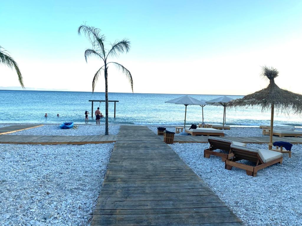博許的住宿－Maison Bellevue - 2 bdrm villa in Borsh beach，海滩上设有长椅和遮阳伞,还有大海