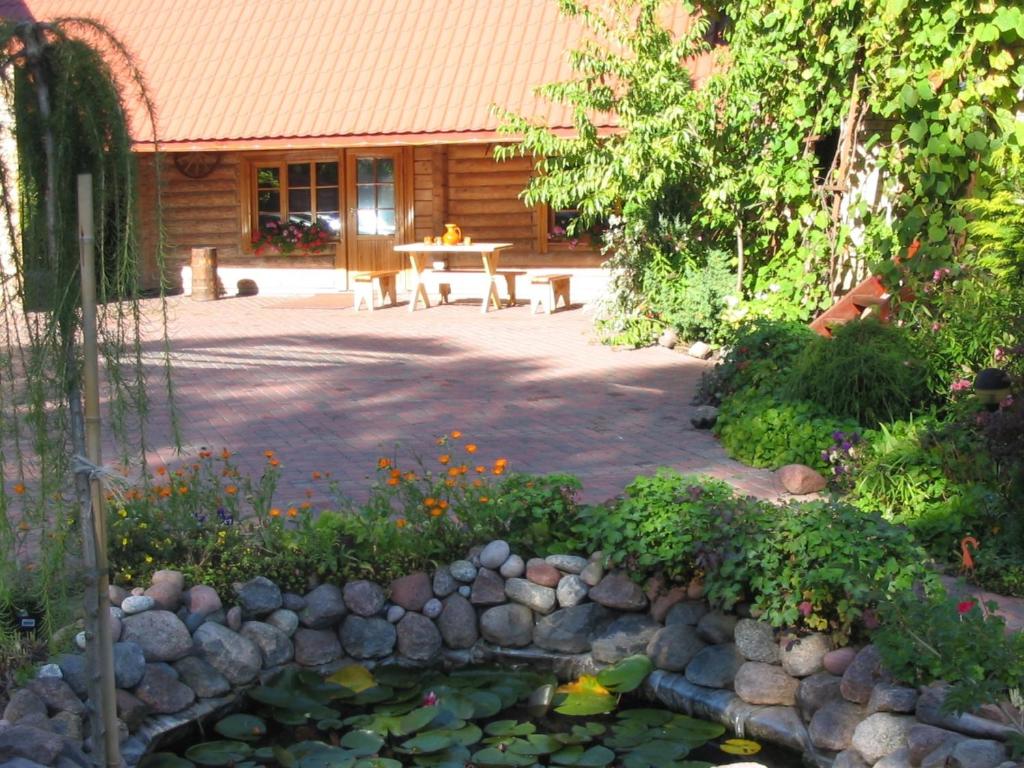 un jardín con una mesa y un estanque con flores en Brīvdienu māja Mētriņi en Ķekava