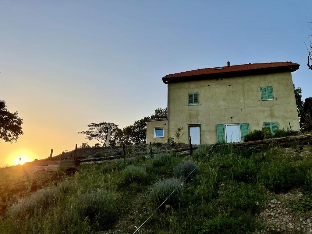 une vieille maison sur une colline avec le coucher du soleil en arrière-plan dans l'établissement Agriturismo Cascina Cornelli, à Sassello