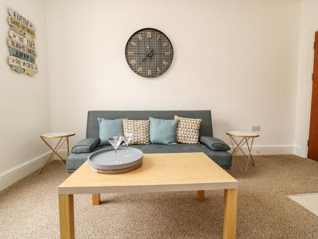 a living room with a couch and a clock on the wall at The Dukes Apartments, Flat 3 in Scarborough