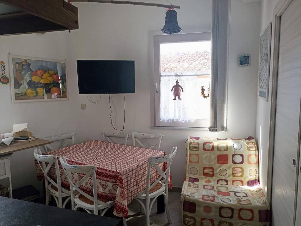 una sala da pranzo con tavolo, sedie e TV di Appartment Carib in Castelbuono a Castelbuono