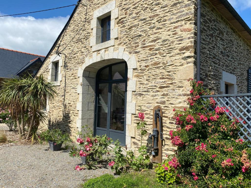 une maison en pierre avec une porte et des fleurs dans l'établissement Chambres d'Hôtes Bella Laïta, à Keranquernat