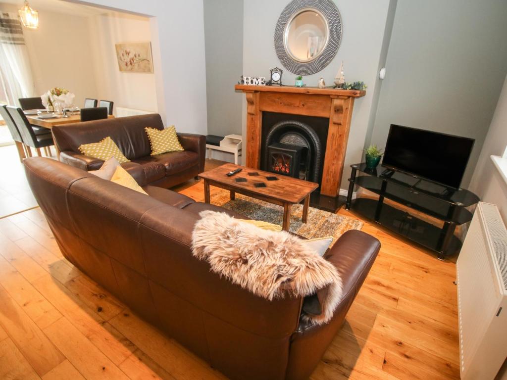 a living room with a brown couch and a fireplace at Pebble Lodge in Kenmare