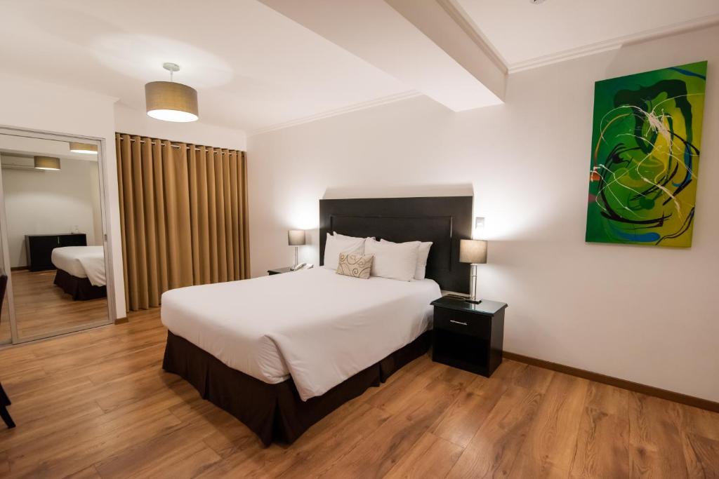 a bedroom with a large white bed and a room at El Polo Apart Hotel & Suites in Lima