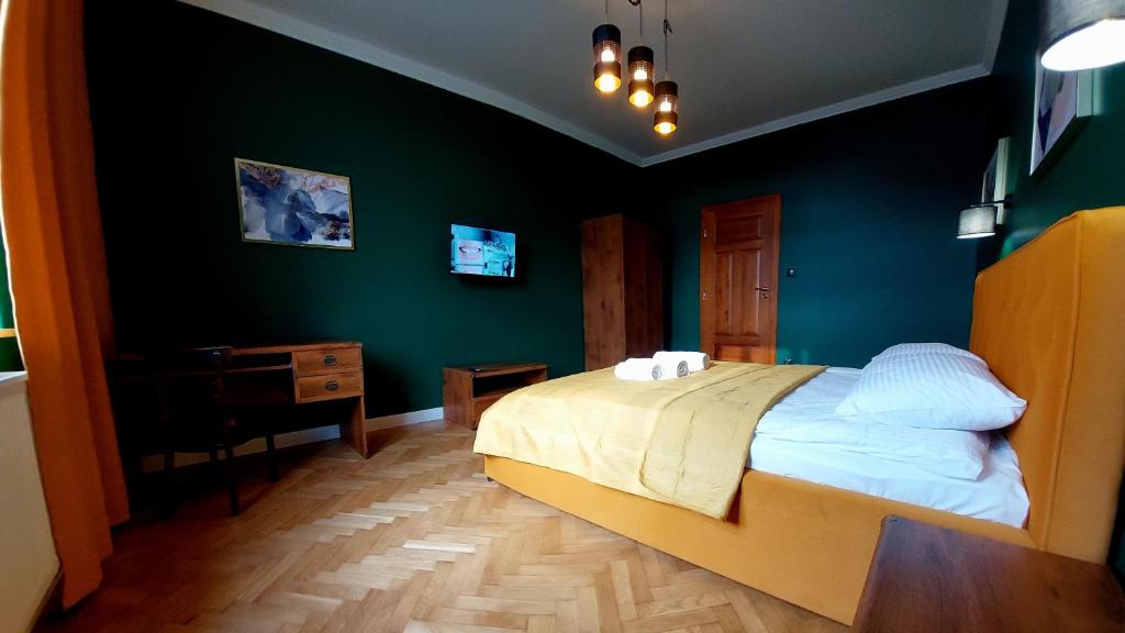 Old Town Plus في تارنوف: غرفة نوم بسرير ومكتب وجدران خضراء