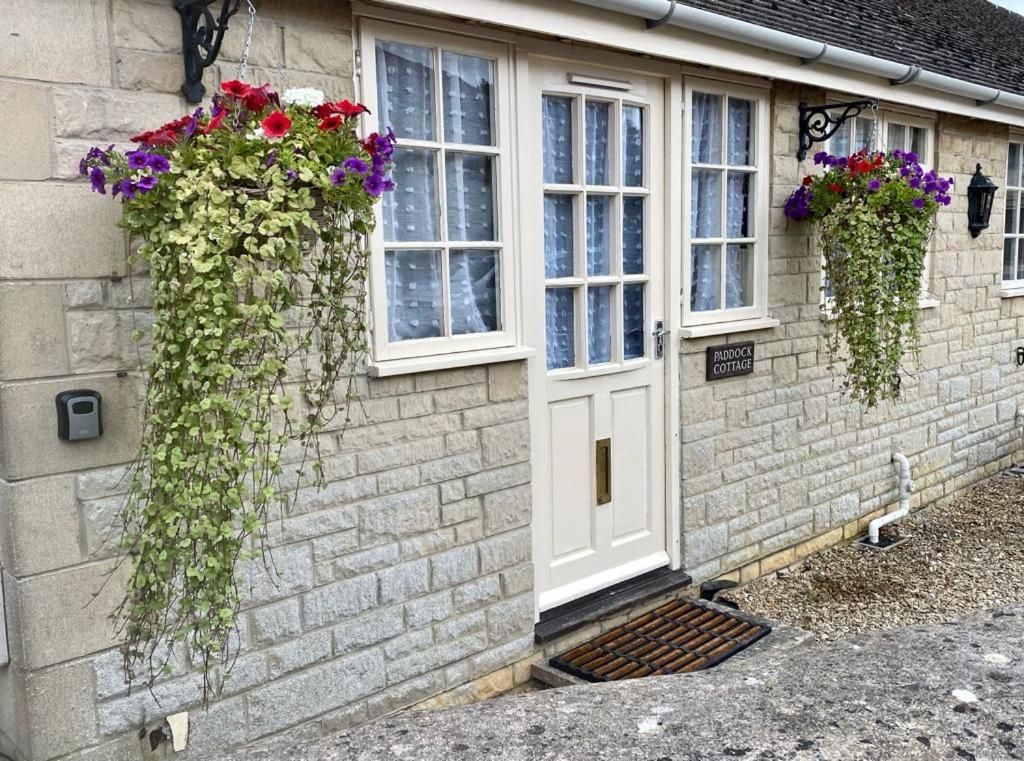 a house with flowers on the side of it at Heart of the village Cotswold Cottage in Crudwell. in Crudwell