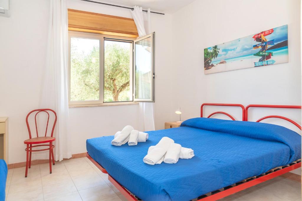 a bedroom with a blue bed with towels on it at Hotel Cylentos Il Villaggio in Santa Marina