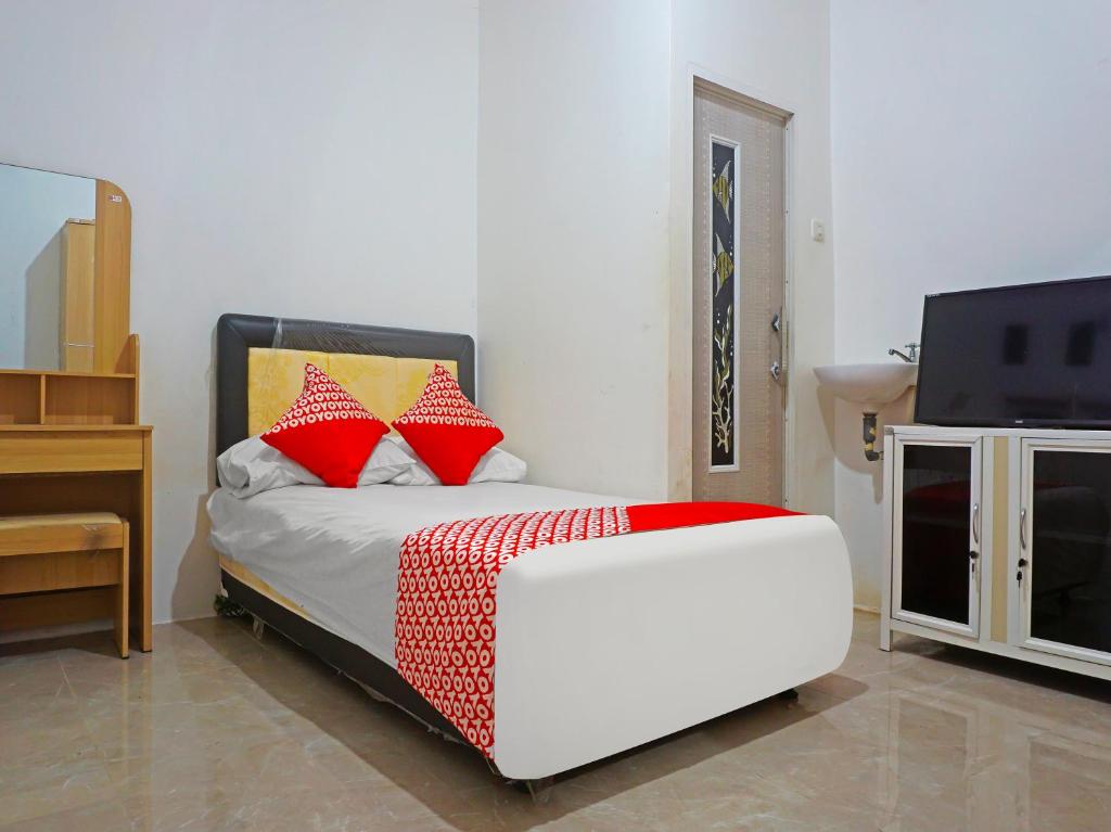 a bedroom with a bed with red pillows and a tv at OYO 91375 Pondok Feby Makassar in Makassar