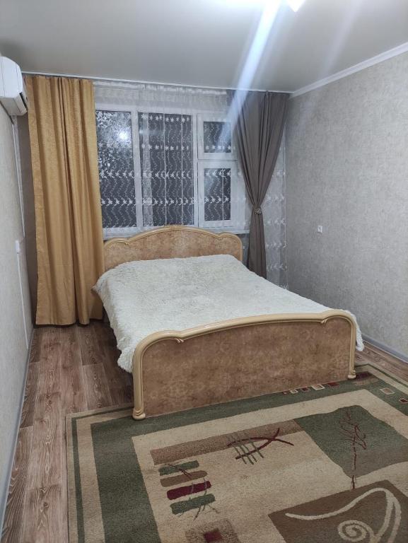 烏拉爾斯克的住宿－Уютная квартира，一间卧室设有床、窗户和地毯。