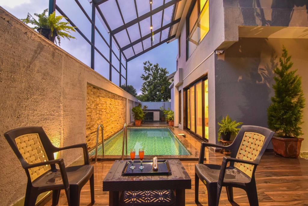 a patio with two chairs and a pool at Castle Rock Villa By Tropicana Stays in Lonavala