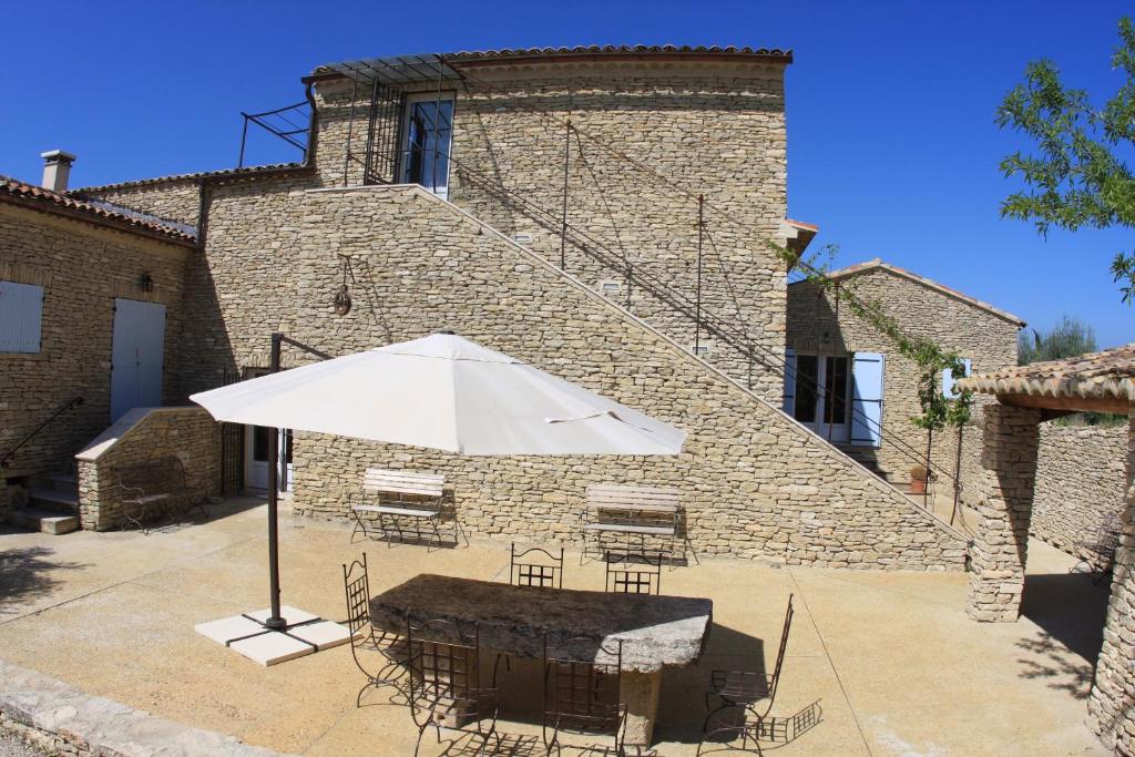 einem Tisch mit einem Regenschirm vor einem Gebäude in der Unterkunft Les Pres de Gordes in Gordes