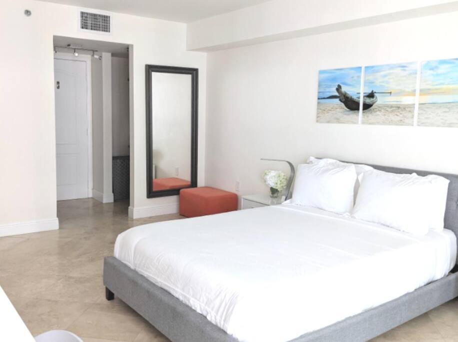 ein weißes Schlafzimmer mit einem großen Bett und einem Spiegel in der Unterkunft Fully Renovated One Bedroom Apartment @ The Club in Miami