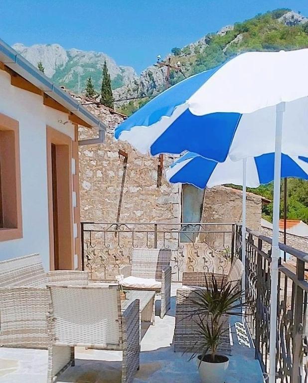 a patio with a blue and white umbrella and chairs at Apartmani Dumezic in Bar